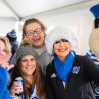 President Mantella gives the "anchor up" sign with Louie and a group of alumni in the Tent
